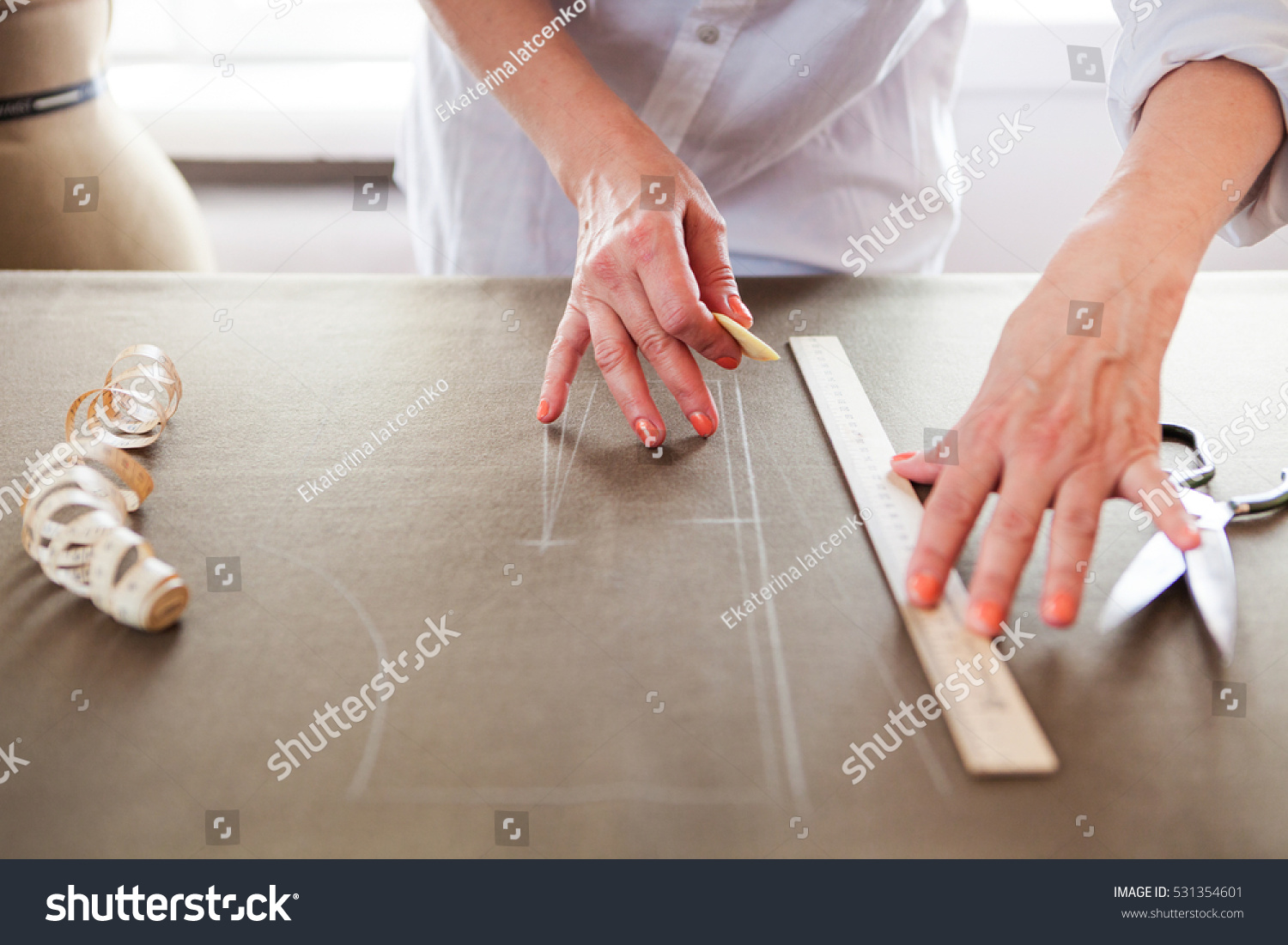 stock-photo-close-up-hands-woman-tailor-working-cutting-a-roll-of-fabric-on-which-she-has-marked-out-the-531354601